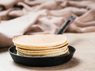 homemade pancakes in iron cast. Stack of pancakes on brown concrete background. Close up.