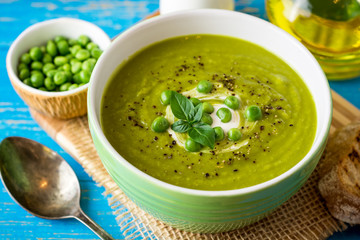 Green pea soup in bowl on wooden table