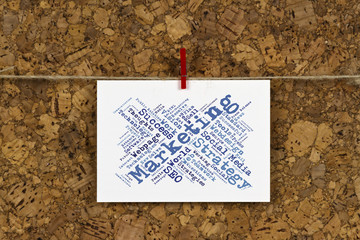 Markering strategy word cloud on business card pinned up on cork board