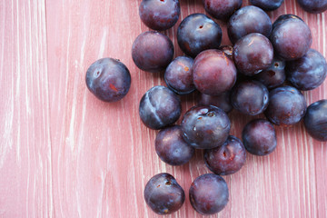 Ripe plums on a pink wooden background