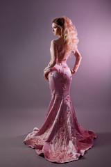 Sexy silhouette of a woman in a luxurious pink dress, back view