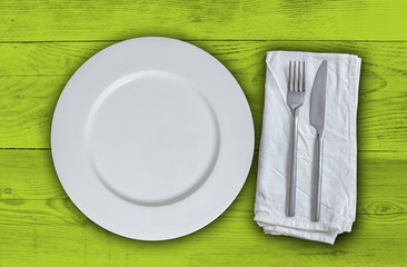 Leerer Teller mit Besteck auf Hellgrünem vintage Holz