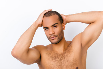 Fototapeta premium Confident andsome young nude man is standing on the pure white background, fixing his perfect hairstyle. So hot and attractive, fashionable and brutal