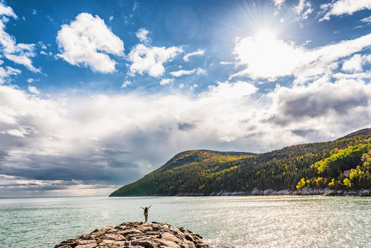 Autumn nature background canadian landscape in Quebec, Canada. Fall season St Lawrence river in Charlevoix region, North America. Tourist with arms up open in freedom happy of travel holidays.