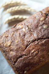 Loaf of fresh bread and ears of wheat, top view