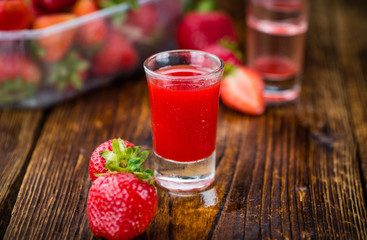 Wooden table with Strawberry liqueur, selective focus