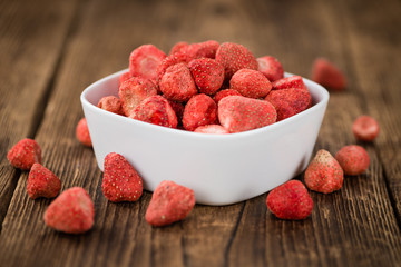 Strawberries (dried) on wooden background; selective focus
