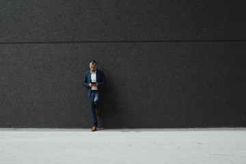 Young business man standing in front of a black building