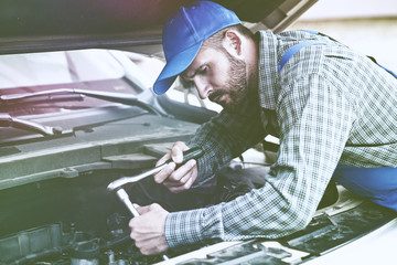 Auto mechanic working with wrench in engine. Car repair service