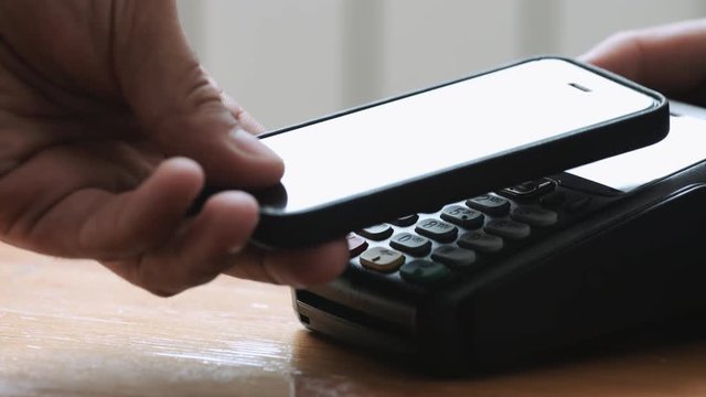 Close-up shot of person using NFC technology on smart phone to pay
