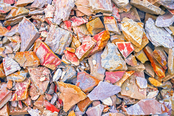 The pattern of the variegated sandstone. A big heap of sandstones, storage space of various natural sandstone. Cracks and colorful layers of sandstone background. Layers of toning colored stones.