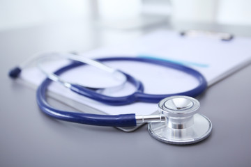 Stethoscope with black medical clipboard on wooden desk