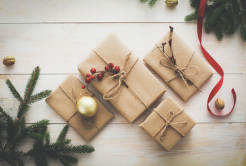 Christmas gift boxes and fir tree branch on wooden table, flat lay