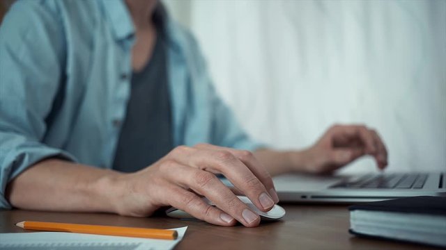 Young guy using laptop in office. Male hands typing message on laptop