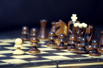 One white pawn fights against black army on chess board.