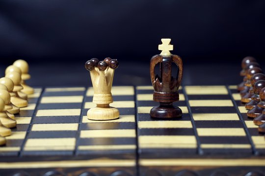 King and Queen chess pieces standing in the middle of a chess board among the other chess.