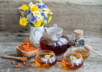 chamomile tea with chamomile flowers and sea-buckthorn on wooden boards
