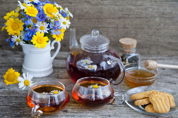 Fototapeta na wymiar chamomile tea with chamomile flowers and sea-buckthorn on wooden boards