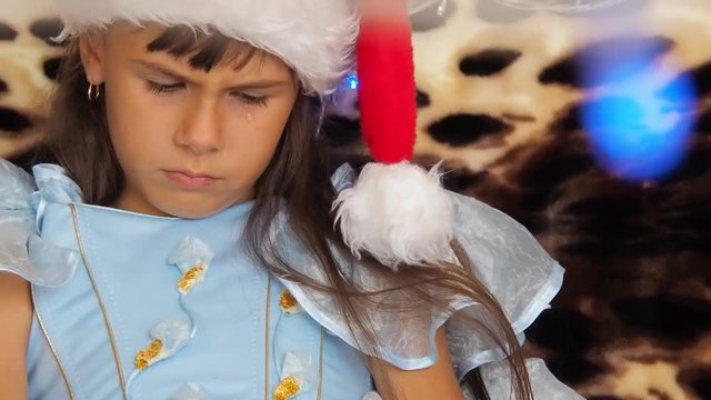 Tears of a child in Christmas. A little girl with sparkles on her face is crying.