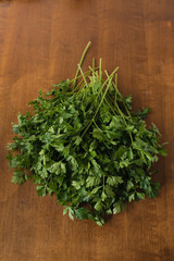 Bunch of fresh, wet garden parsley stems with little imperfections on wooden background