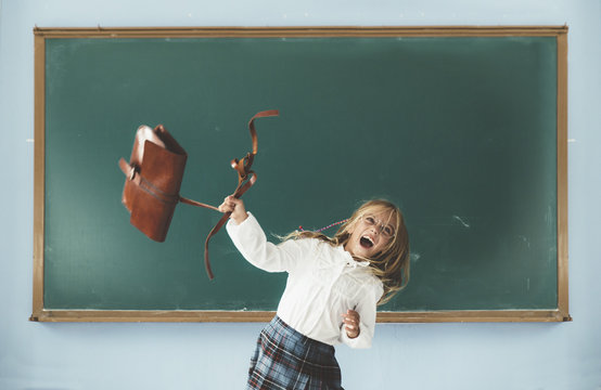 Girl throwing backpack in classroom