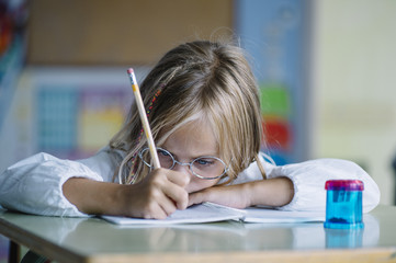 Thoughtful girl writing in class