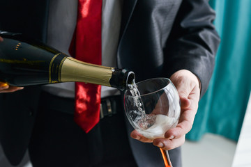 man filling decorated glass with champagne