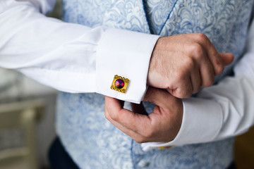 man in a tux fixing his cufflink