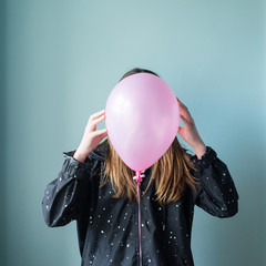 teen girl with pink balloon over her face