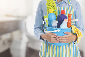 woman with cleaning equipment ready to clean house on bathroom background