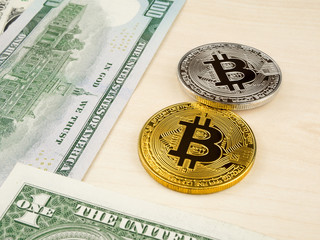 Golden and silver bitcoin coin on us dollars close up.