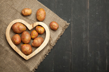 Obraz premium Potatoes on a black wooden background