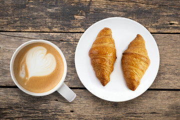 Croissant with coffee In white plate placed on a wooden table top view