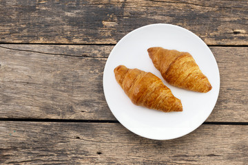 Croissant In white plate placed on a wooden table top view