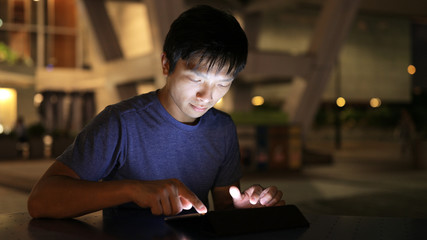 Man using tablet computer at night