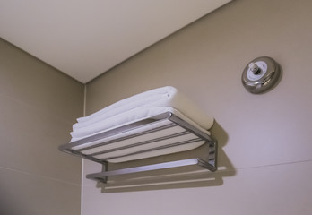 Stainless steel rack on grey tile wall with white towel in bathroom