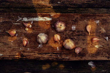 Low key garlic on an old wooden surface in a sun spots. Top view flat lay.
