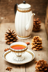 Cup of tea on a wooden background with anise, cinnamon, and pine cones. Selective focus.