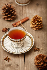 Cup of tea on a wooden background with anise, cinnamon, and pine cones. Selective focus. Rustic.