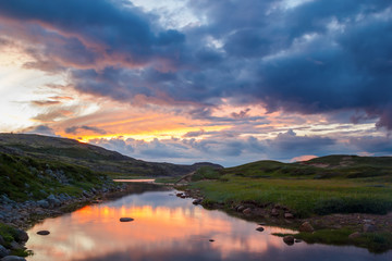 Fototapeta na wymiar The bright sunset reflected in the river in the tundra on the Kola Peninsula