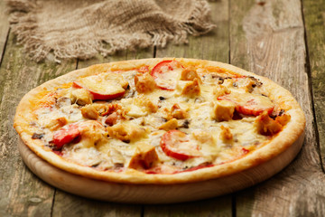 Chicken pizza on a rustic wooden table. Selective focus.