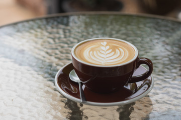 hot coffee latte with beautiful foam art on glass table.outdoor cafe