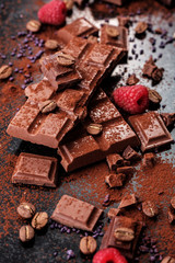Broken chocolate pieces and cocoa powder on marble.