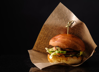 Fresh Fish burger with vegetables on a dark background.