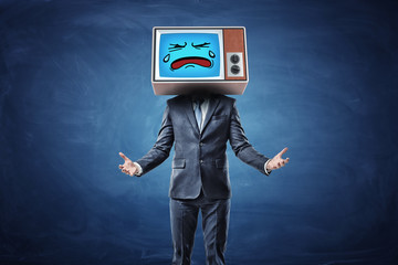 A businessman with hands turned in front of him with palms up and wearing a TV with a sad crying face on his head.