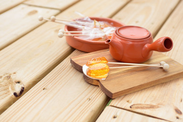 Candy lollipop and teapot on wooden background