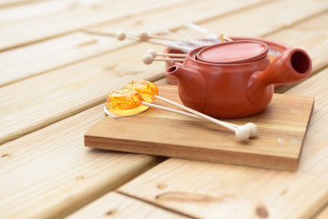 Candy lollipop and teapot on wooden background