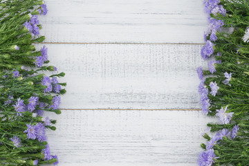 Purple cutter flowers with green branches on white wood background with copy space