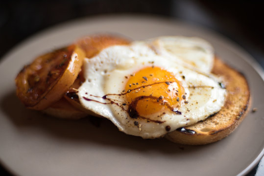 Fried egg sunny side up on a toast with tomato