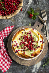 Homemade tender curd casserole with juicy berries cranberries on a gray stone background with forks and branches of berries. Top View.
